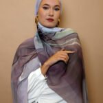 Elegant woman wearing a mauve and grey luxury patterned hijab with soft gradient tones, styled for modest high fashion.