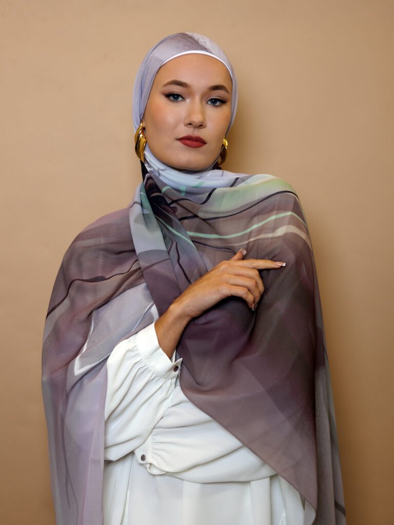 Elegant woman wearing a mauve and grey luxury patterned hijab with soft gradient tones, styled for modest high fashion.