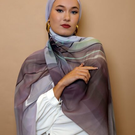 Elegant woman wearing a mauve and grey luxury patterned hijab with soft gradient tones, styled for modest high fashion.