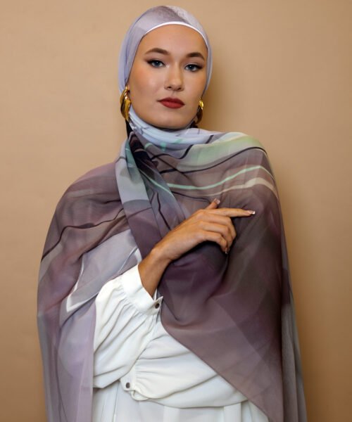 Elegant woman wearing a mauve and grey luxury patterned hijab with soft gradient tones, styled for modest high fashion.